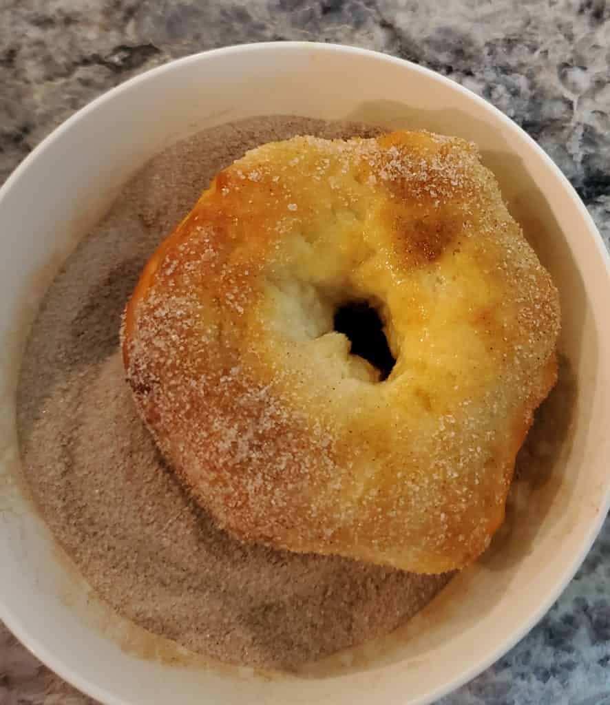 Dredging the Air fry doughnut in cinnamon and sugar