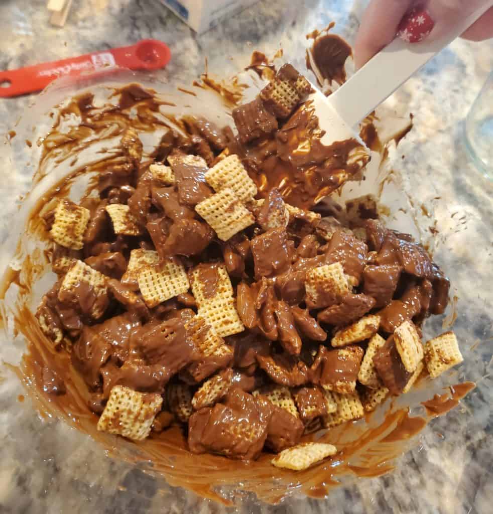Mixing the cereal into the melted concoction for this puppy chow recipe