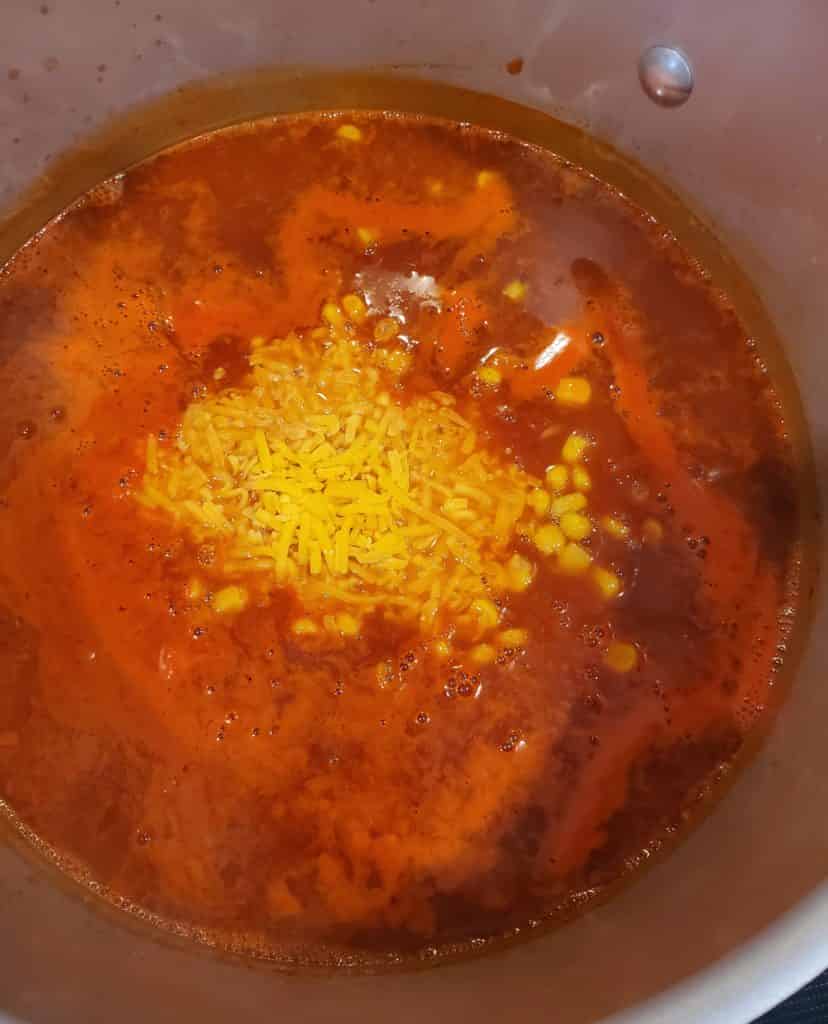 Adding corn and cheese to the soup