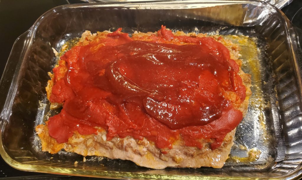 The meatloaf recipe topped with the ketchup glaze and ready to finish baking in the oven