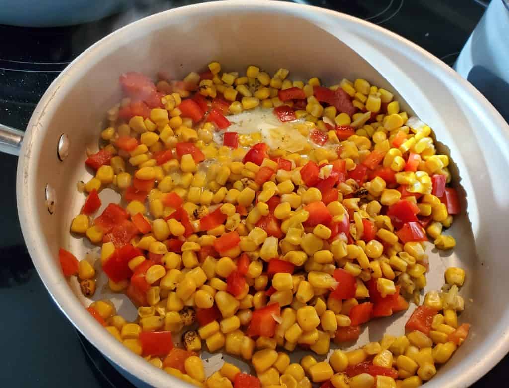 Fire-roasted corn and red peppers in a medium skillet cooking with an additional 1 tablespoon of butter
