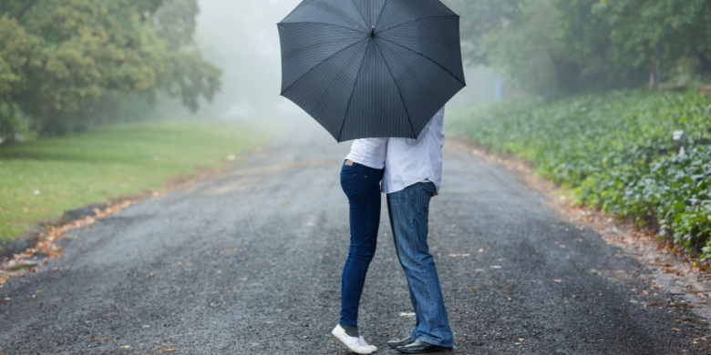 A couple kissing behind an umbrella