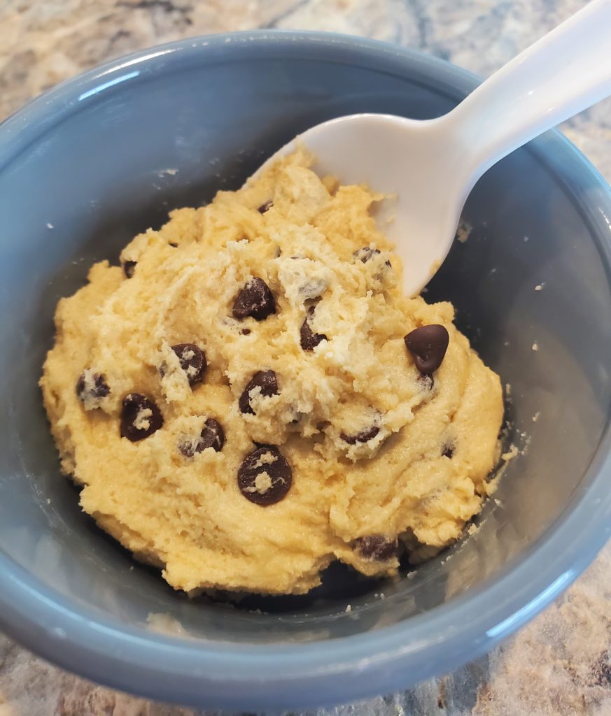 A "scoop" of edible chocolate chip cookie dough in a bowl with a spoon ready to be devoured!
