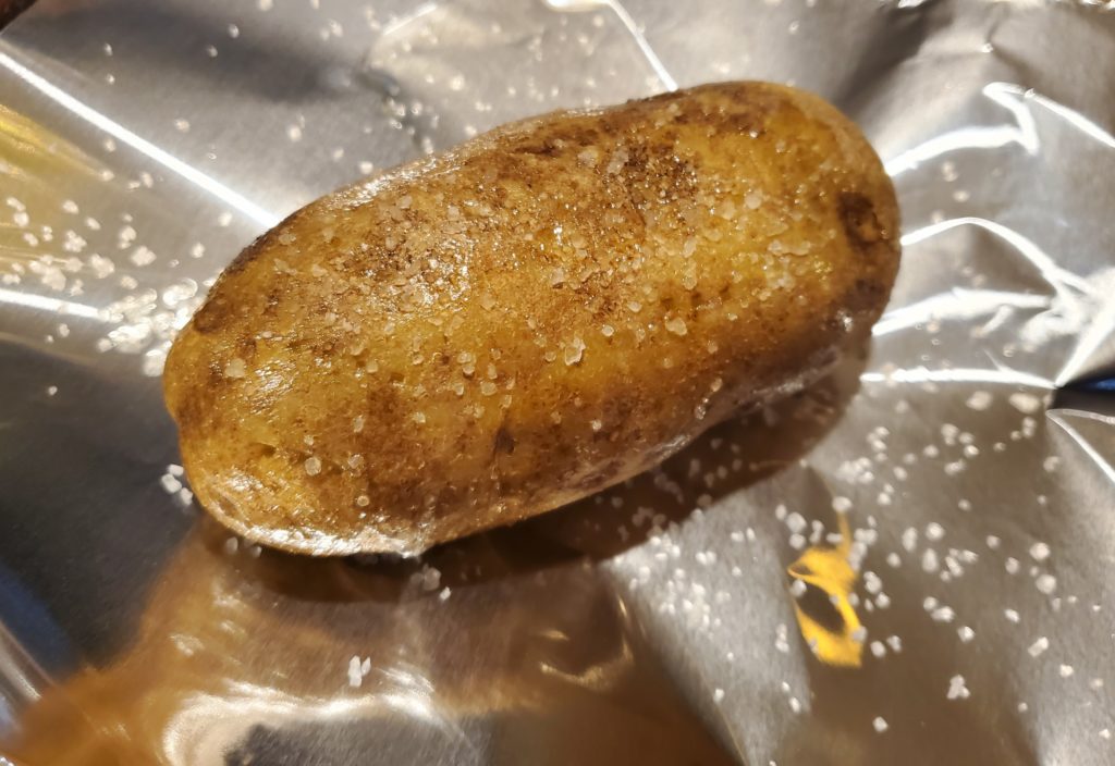 A baked potato that has been drizzled with oil and sprinkled with coarse sea salt