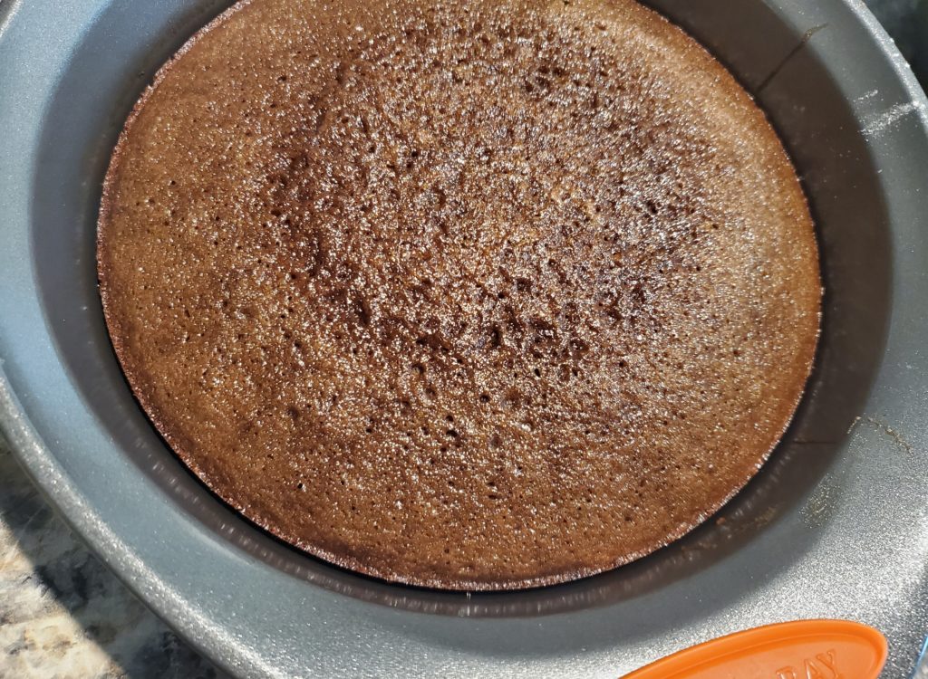 The baked fudgy chocolate cake shrinking away from the sides of the pan.