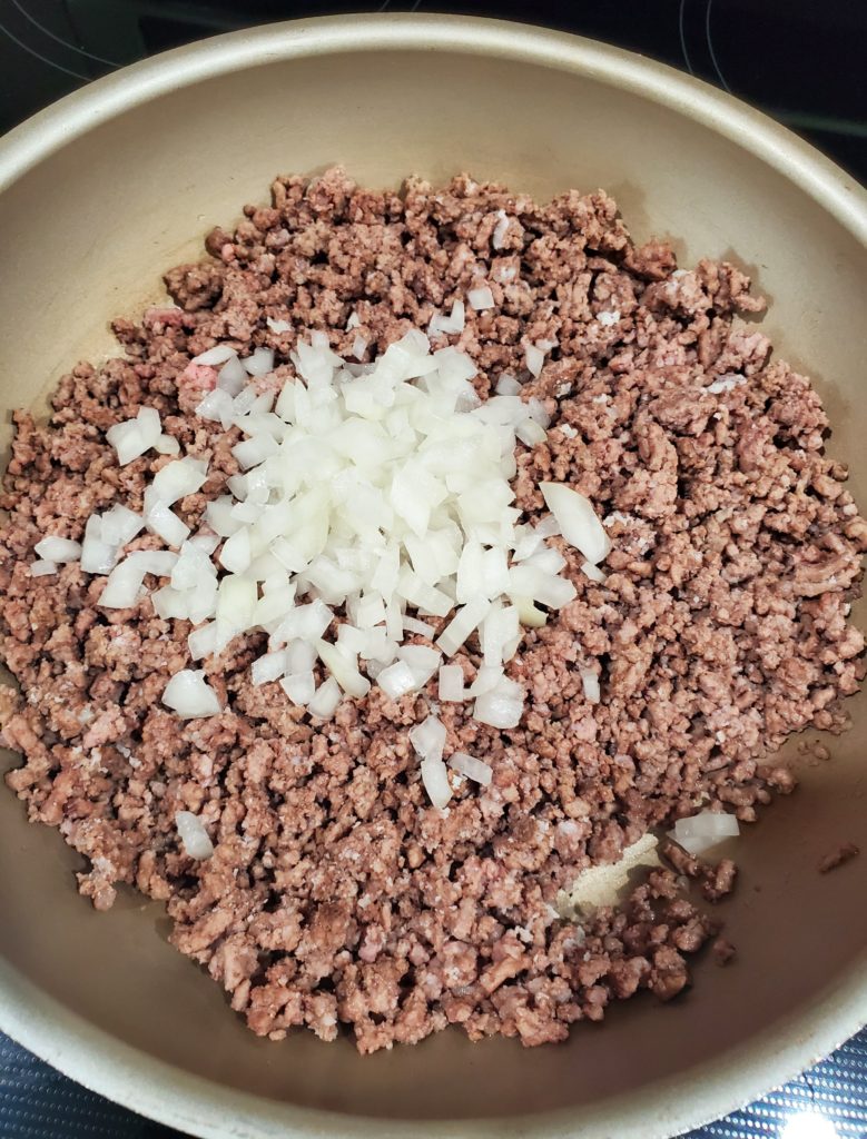 The mostly cooked ground beef with the diced onion added in