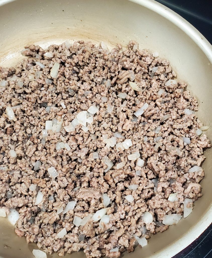The fully cooked ground beef with the cooked onion that is starting to get translucent