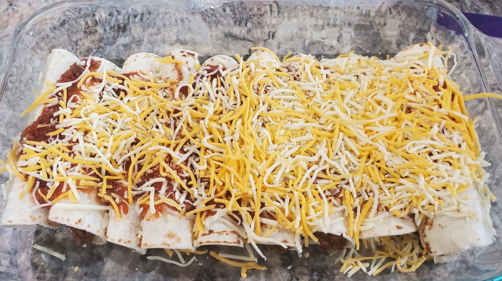 Prepared beef enchiladas covered in salsa and shredded cheese