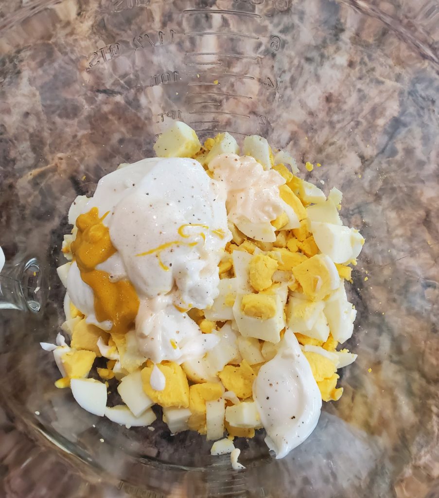 All of the egg salad ingredients together in a mixing bowl before being mixed