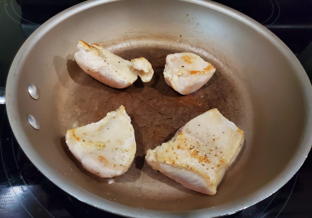 Chicken breasts cooking on the stove in a skillet for this easy chicken dinner idea