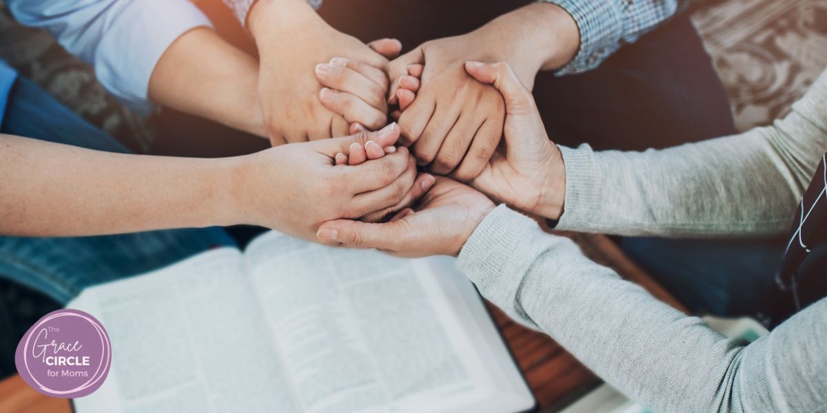 Women's hands shown holding each other over a Bible to represent the community for Christian moms: The Grace Circle for Moms